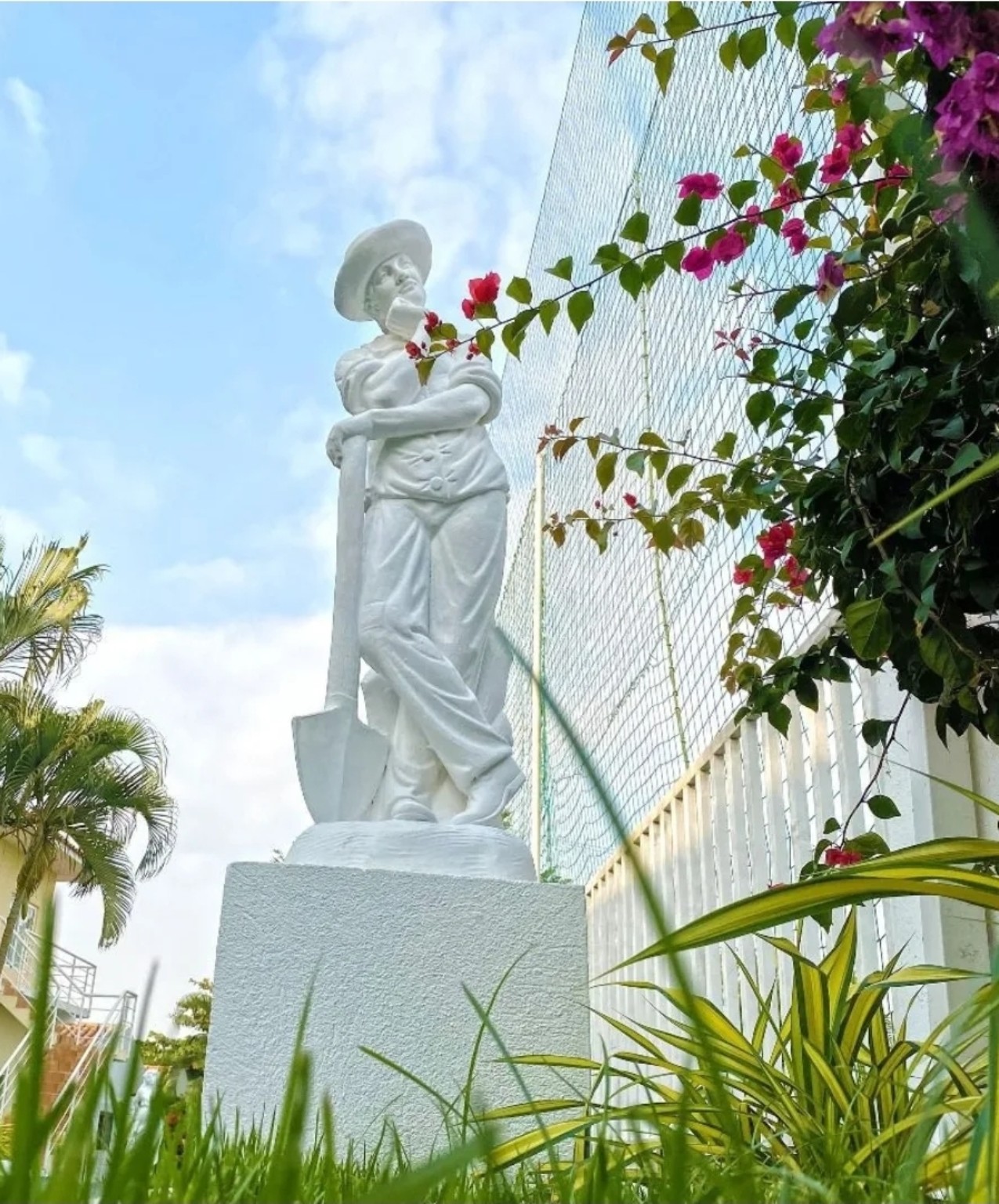 Escultura branca entre flores e plantas no jardim