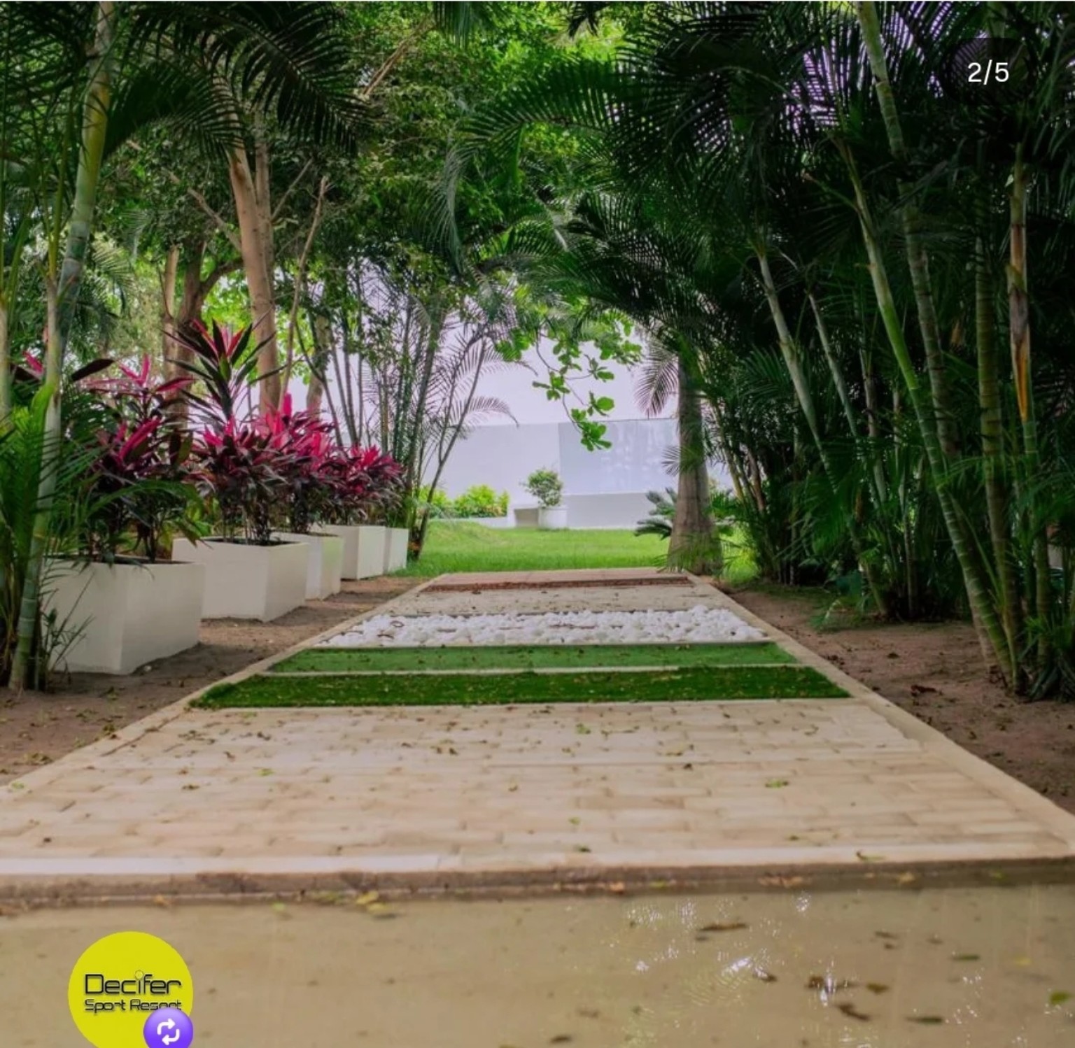 Percurso do jardim sensorial com diferentes pisos, plantas e canteiros brancos